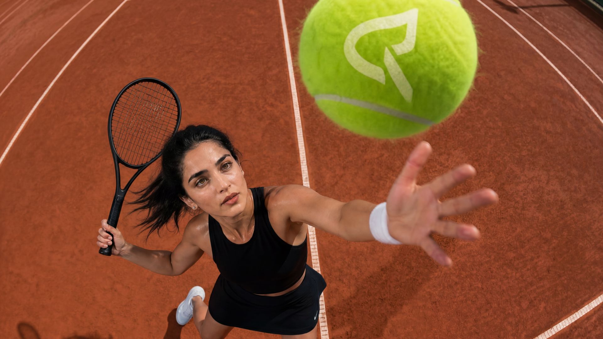 Tennis player mid-serve — dynamic overhead angle